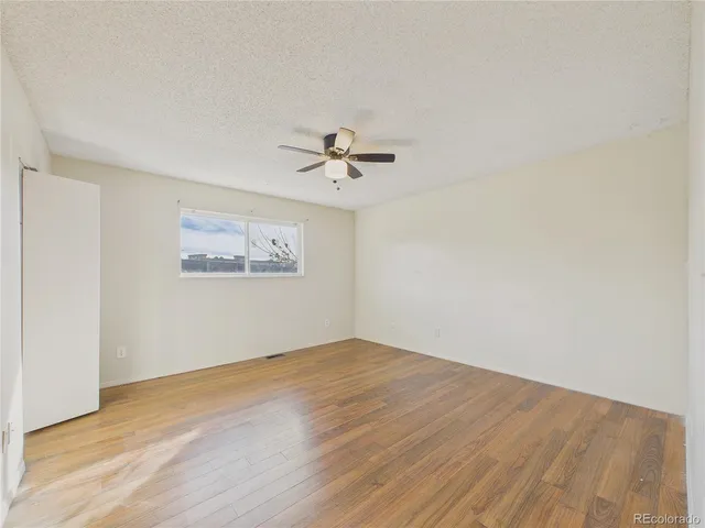 an empty room with a ceiling fan and wooden floor