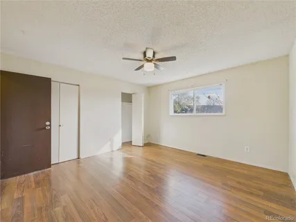 an empty room with wooden floor and ceiling fan