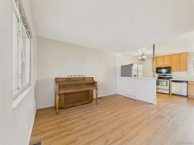 a view of kitchen and empty room with wooden floor