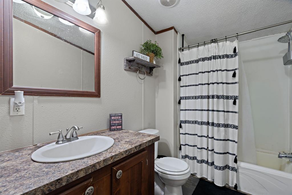 2005 Atticus Court Springtown, TX 76082 - Photo 8 of 15 a bathroom with a granite countertop sink a large mirror and a toilet