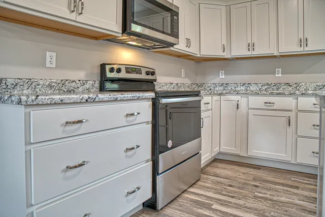 a kitchen with granite countertop white cabinets stainless steel appliances and sink