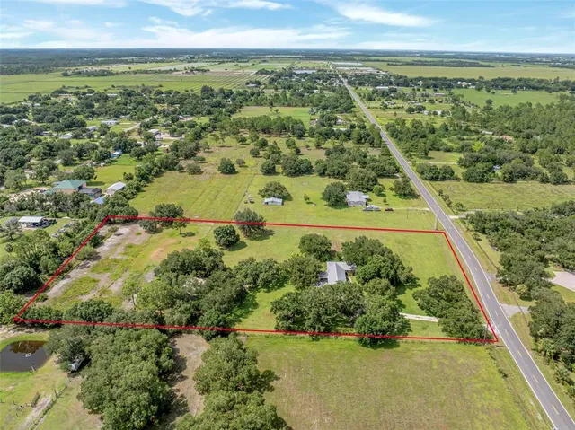 an aerial view of residential houses with outdoor space and trees
