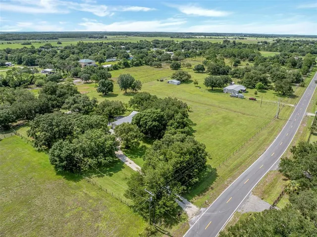 an aerial view of residential houses with outdoor space and trees