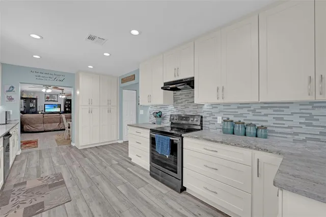 a kitchen with stainless steel appliances granite countertop a stove and white cabinets