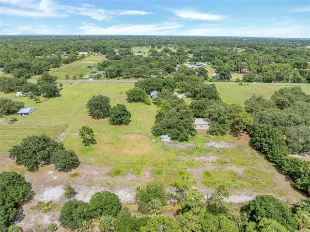an aerial view of residential houses with outdoor space and trees