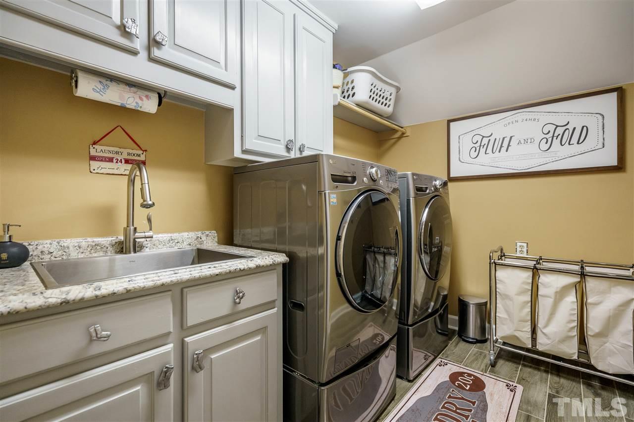 1028 Mersey Lane Raleigh, NC 27615 - Photo 22 of 30 Laundry Room with Gray cabinets, custom pulls, granite tops, SS sink and tile floors.