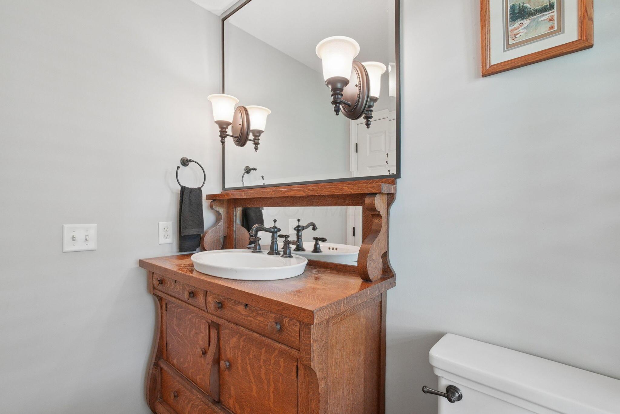 9435 Concord Road Powell, OH 43065 - Photo 14 of 77 Custom wood vanity with integrated basin sink, oil-rubbed bronze faucet, and framed mirror