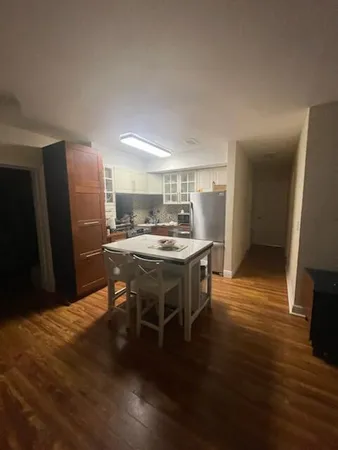 a kitchen with stainless steel appliances kitchen island granite countertop a table chairs and a refrigerator