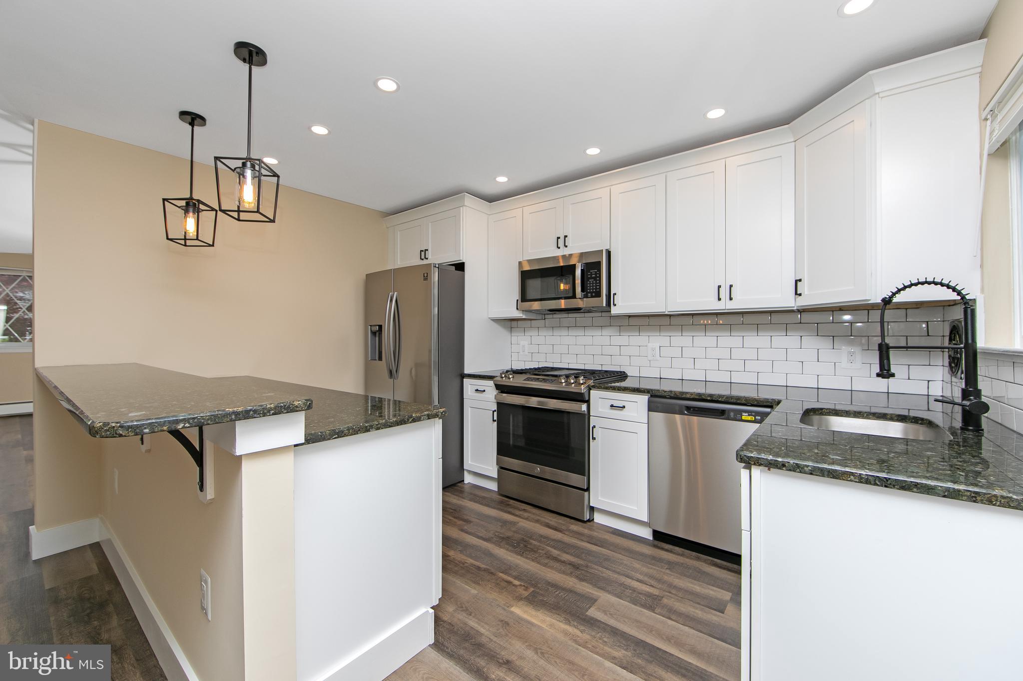 a kitchen with stainless steel appliances granite countertop a sink stove microwave and refrigerator