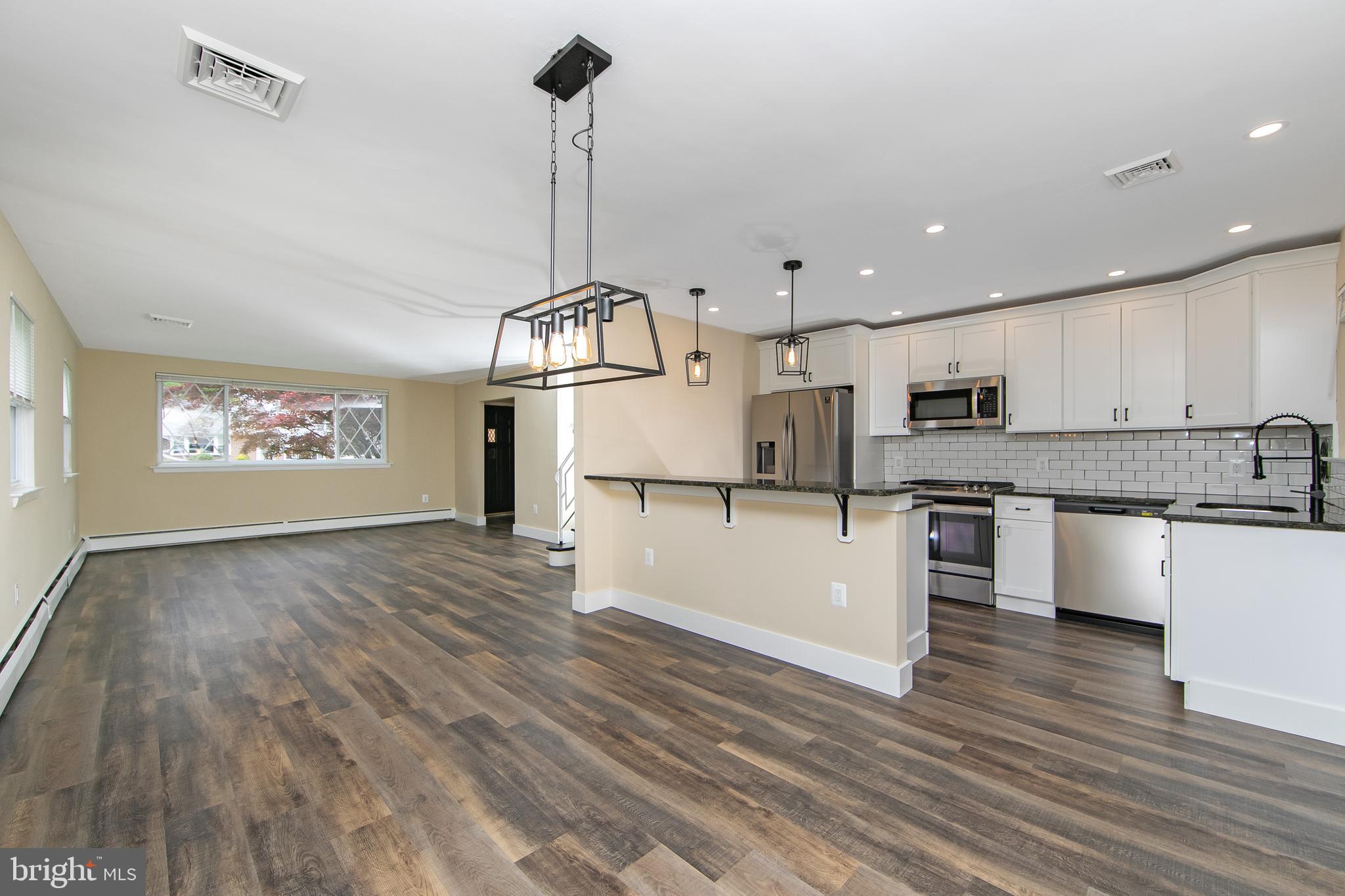 334 Parham Road Springfield, PA 19064 - Photo 12 of 41 a kitchen with stainless steel appliances granite countertop a refrigerator a stove top oven a sink dishwasher and white cabinets with wooden floor