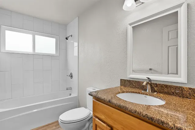 a bathroom with a granite countertop sink mirror toilet and bathtub