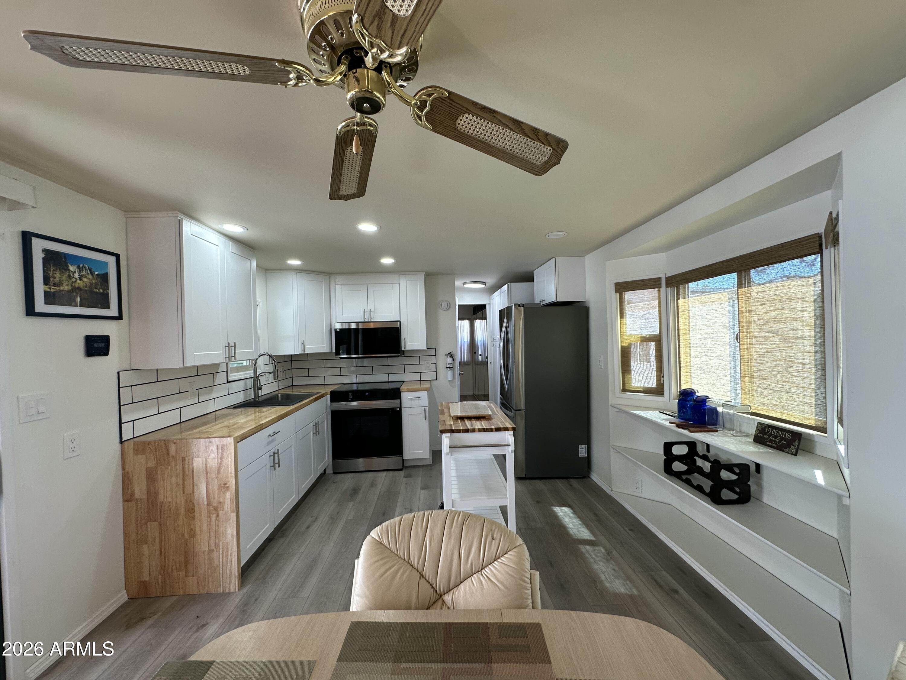 111 South Greenfield Road, Unit 575 Mesa, AZ 85206 - Photo 2 of 14 a kitchen with stainless steel appliances granite countertop a refrigerator oven stove a sink dishwasher a dining table and chairs with wooden floor