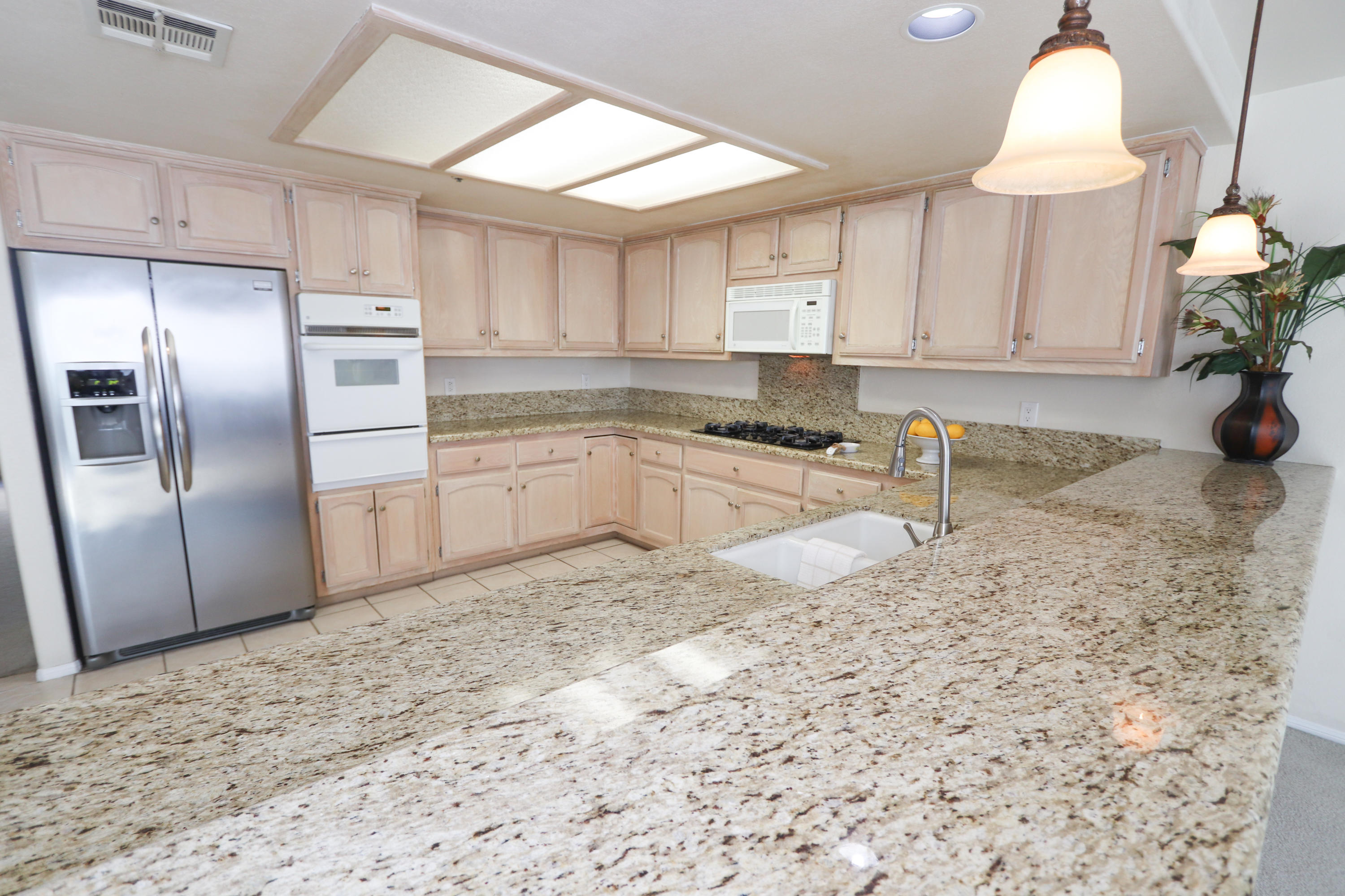 68250 Risueno Road Cathedral City, CA 92234 - Photo 6 of 19 a kitchen with granite countertop a sink a stove and a refrigerator