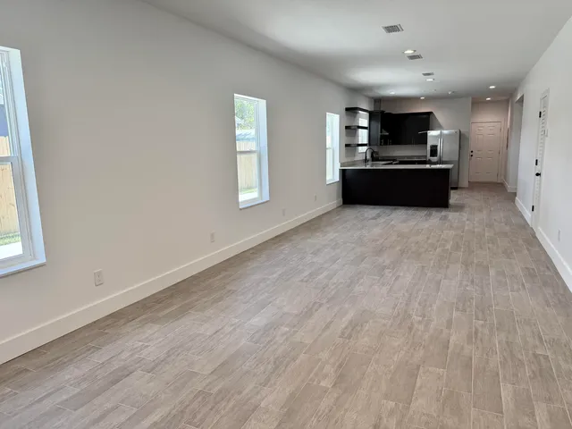 an empty room with wooden floor cabinet and windows