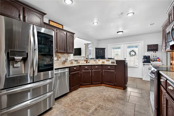 a kitchen with stainless steel appliances kitchen island granite countertop a refrigerator oven a sink dishwasher and cabinets