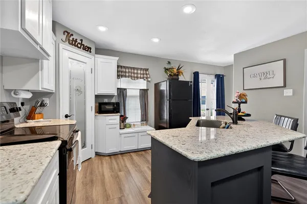 a kitchen with granite countertop cabinets a refrigerator a sink a stove and island