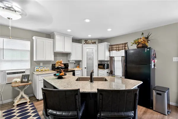 a kitchen with stainless steel appliances kitchen island granite countertop a sink a stove a refrigerator and cabinets