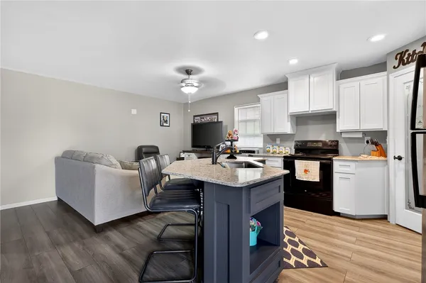 a kitchen with stainless steel appliances granite countertop a sink dishwasher stove refrigerator and cabinets with wooden floor