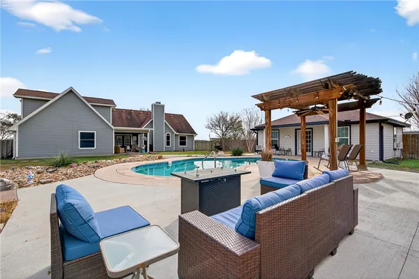a view of a house with swimming pool and a dining table and chairs under an umbrella