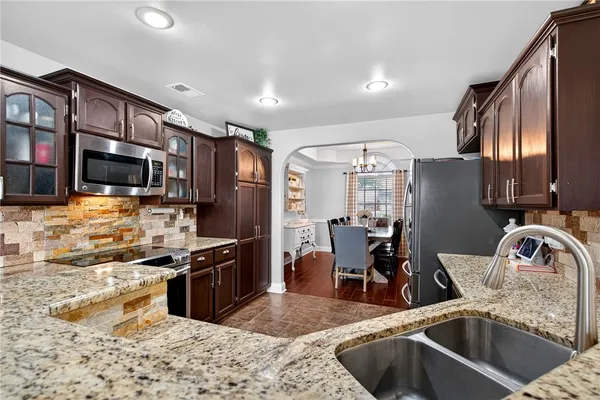 a kitchen with stainless steel appliances granite countertop a sink refrigerator and cabinets