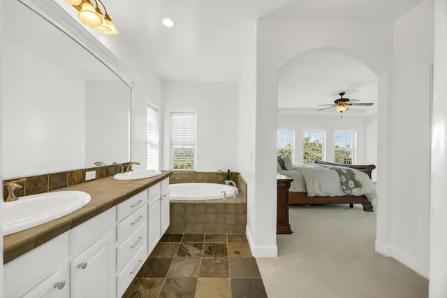 a en suite bathroom with a double vanity sink a mirror and a bathtub