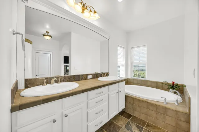 a spacious bathroom with a granite countertop tub sink and mirror