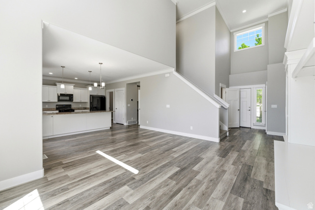 1614 Aspen Loop Provo, UT 84606 - Photo 7 of 47 Open-concept living space featuring wood-finish flooring, a two-story foyer with a transom window, white kitchen cabinetry with a contrasting countertop, and a built-in shelving unit
