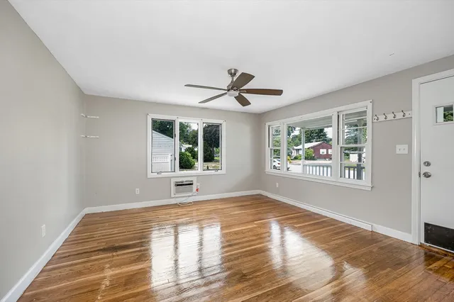a view of an empty room with a window and wooden floor