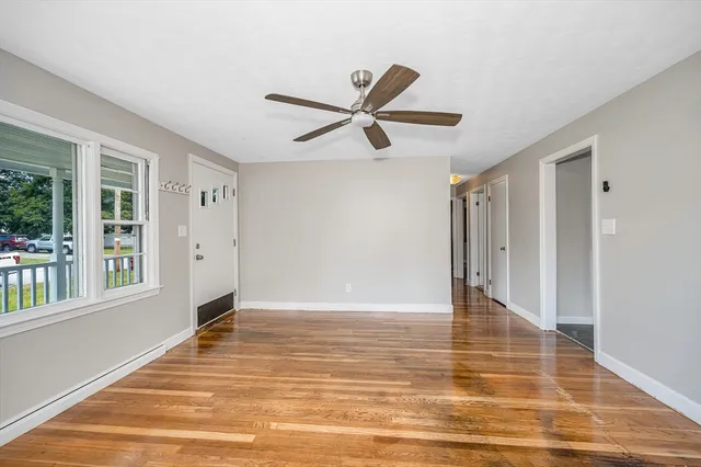 a view of an empty room with window and a ceiling fan