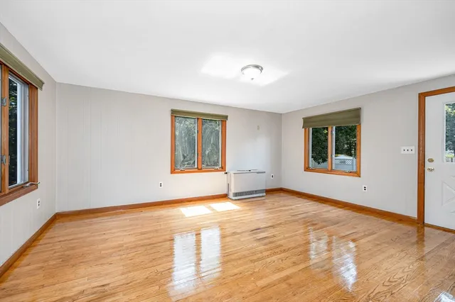 a view of an empty room with window and wooden floor