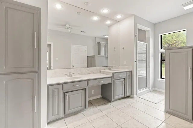 a bathroom with a granite countertop sink two mirror and a shower