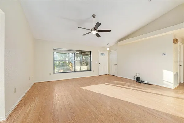 a view of an empty room with a window and wooden floor