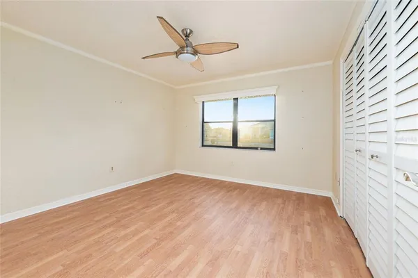 an empty room with closet and a ceiling fan