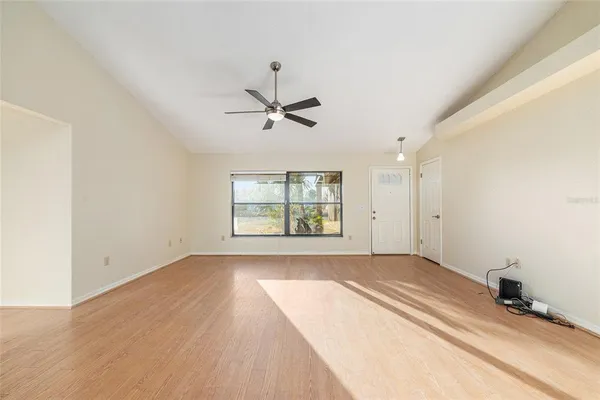 a view of empty room with wooden floor and fan
