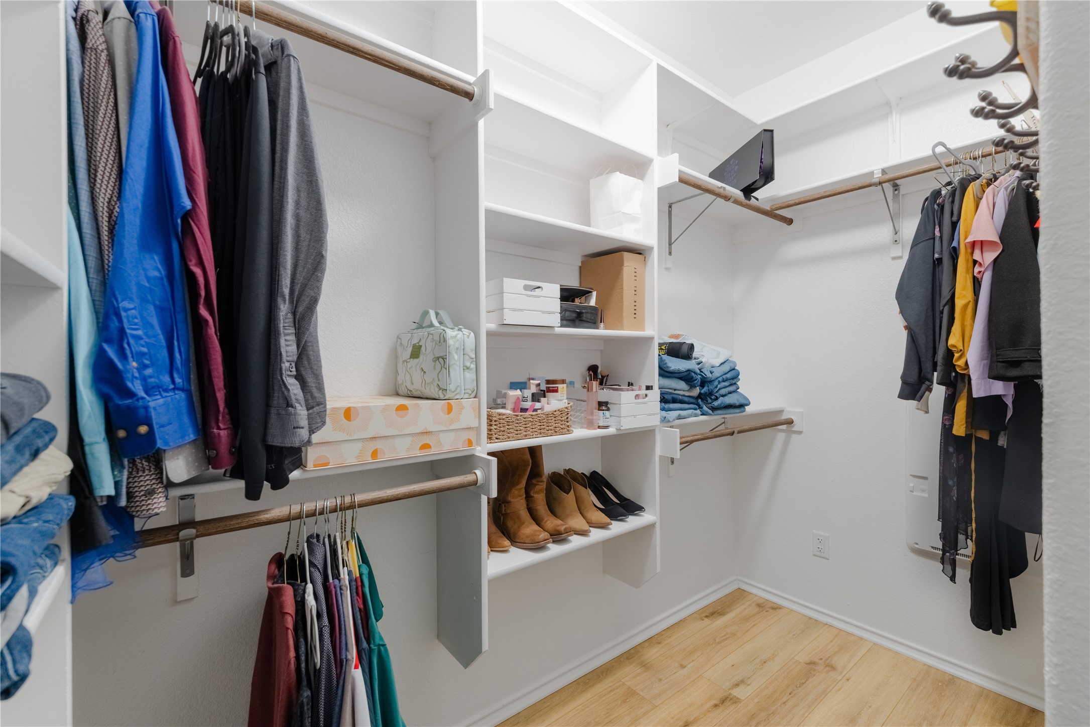 425 Perfect World Loop Jarrell, TX 76537 - Photo 14 of 29 White-painted walk-in closet featuring wood-finish flooring, multiple hanging rods, and built-in shelving