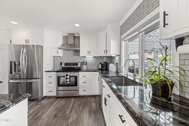 a kitchen with granite countertop a refrigerator stove and sink