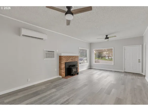 a view of an empty room with wooden floor fireplace and a window