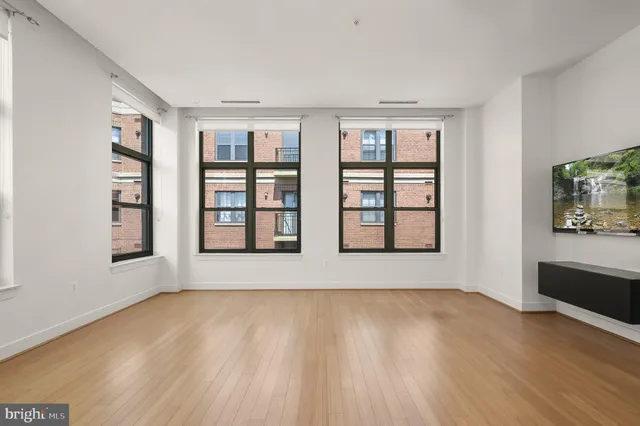 a view of an empty room with window and wooden floor