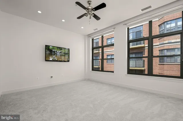 a view of an empty room with a window and a ceiling fan