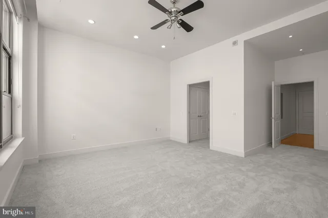 an empty room with closet and a ceiling fan