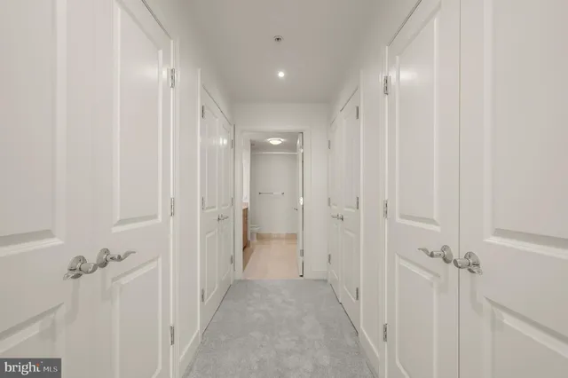 a view of a hallway with closet and a bathroom