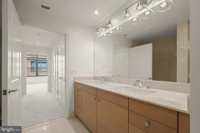 a spacious bathroom with a granite countertop double vanity sink a mirror and shower