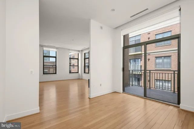 a view of an empty room with window and wooden floor