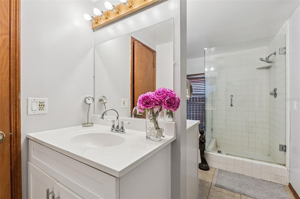 611 North Forsyth Road Orlando, FL 32807 - Photo 17 of 36 a bathroom with a shower sink vanity and mirror