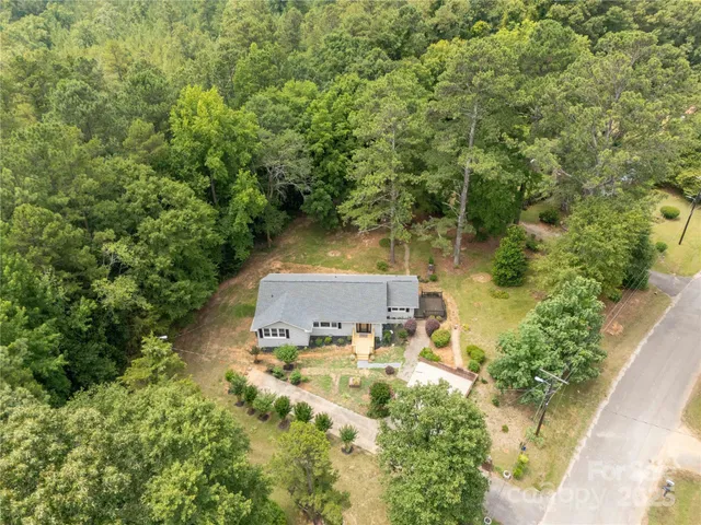 an aerial view of residential house with outdoor space and trees all around