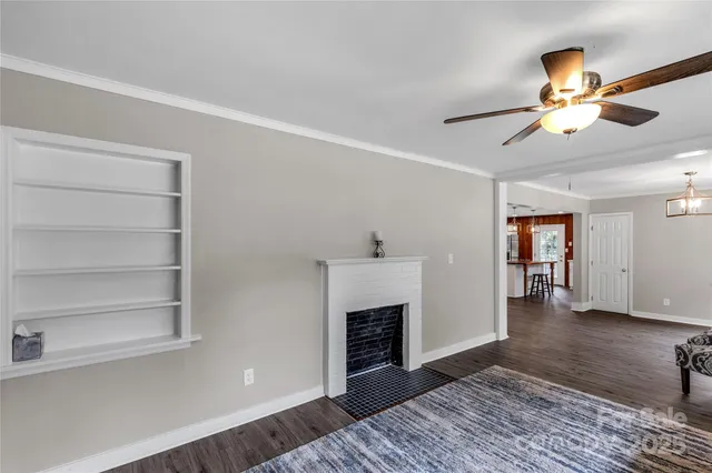 a view of a livingroom with a fireplace a ceiling fan and wooden floor