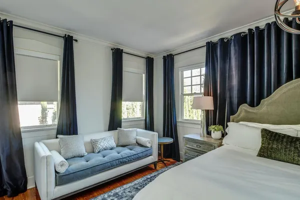 a bedroom with a bed couch and windows