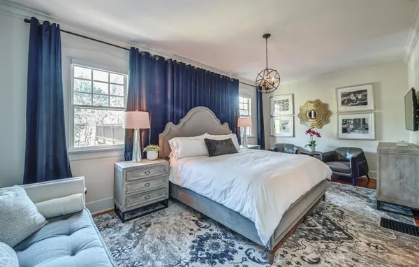 a bedroom with a large bed couch and windows