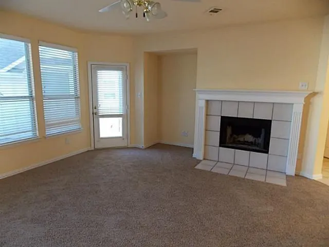 an empty room with windows and fireplace