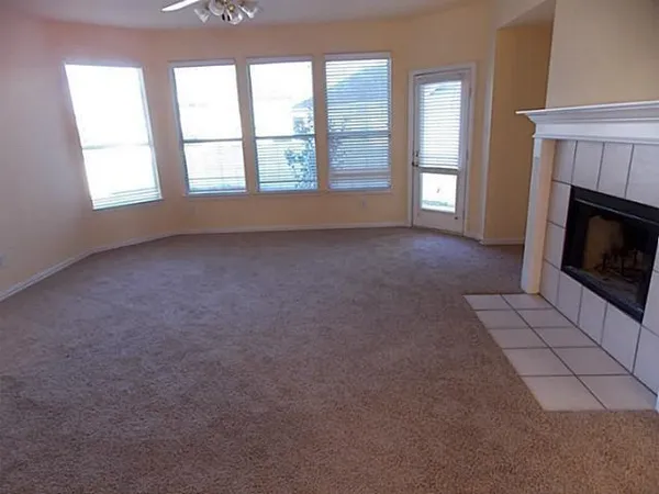 an empty room with windows and fireplace